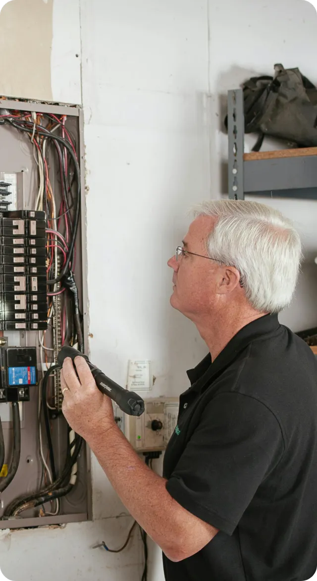 Home inspector examining an electrical panel during a 4-point insurance inspection in Orlando.