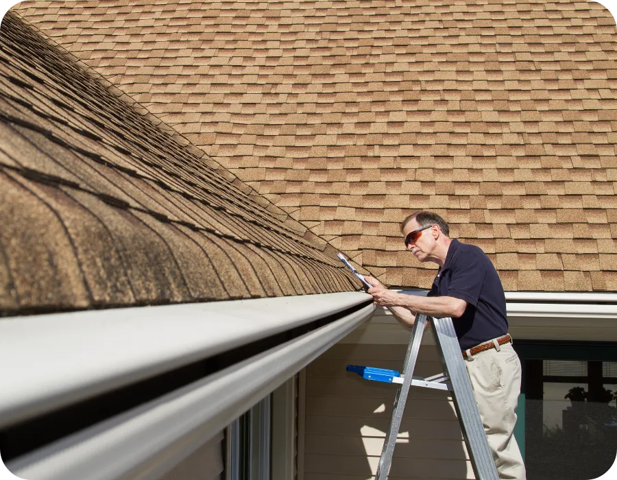Home inspector standing on a ladder examining a residential roof with brown shingles, representing professional home inspection services in Orlando.