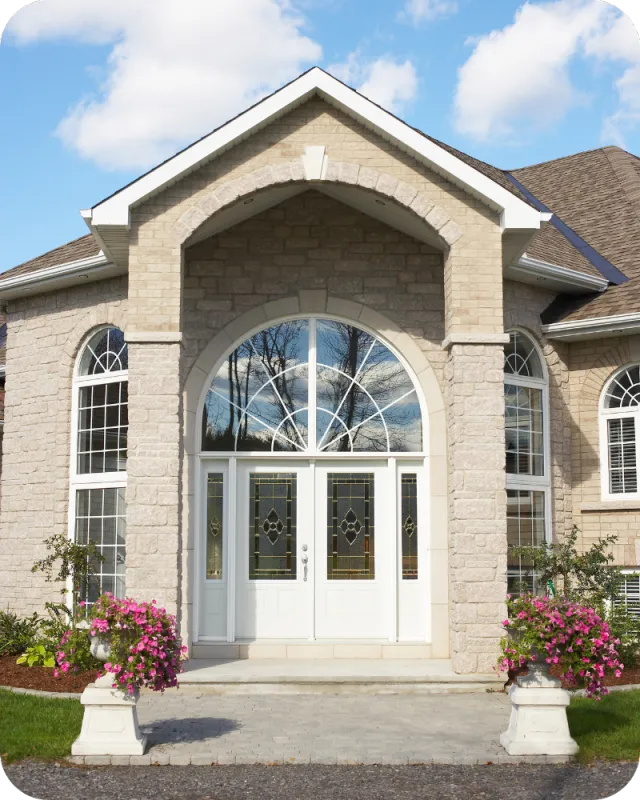 Front exterior of a modern home with arched entryway, large windows, and landscaped flower planters, representing a well-maintained property after inspection.